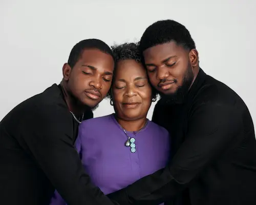 2 young men hugging her mother